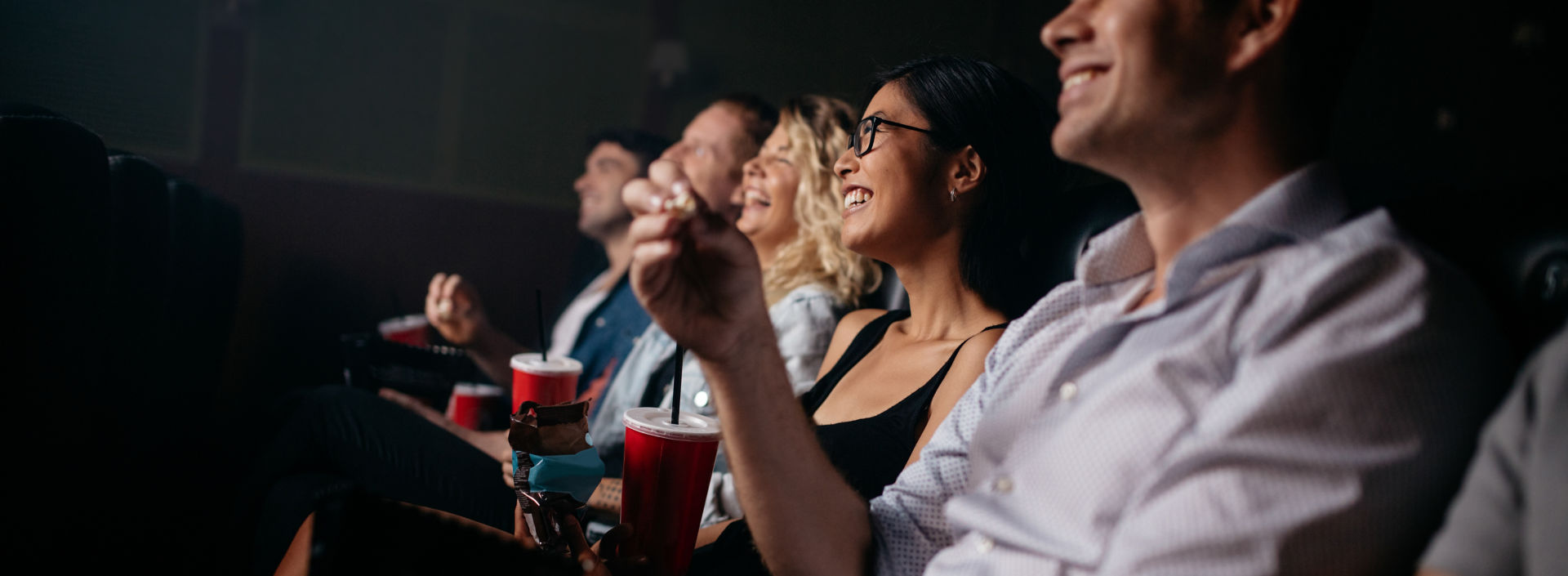 Group of people in movie theater with popcorn and drinks.
